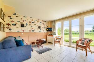 ein Wohnzimmer mit einem blauen Sofa und einer Fensterwand in der Unterkunft Les Maisons de Belle Dune - maeva Home - Maison 4 Pièces 8 Personnes - Prestige MAE-7746 in Fort-Mahon-Plage