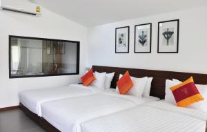two beds in a room with white and orange pillows at Family House Zen Boutique Resort in Pai