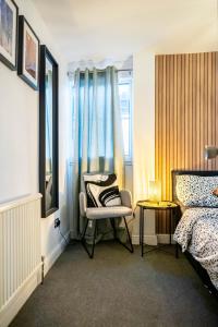 1 dormitorio con silla, cama y ventana en COMFORTABLE SPARE ROOM with KING SIZE BED, Near Sheffield Centre, en Heeley