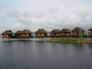a row of houses on a dock in the water at Golden Island Cottages Thale U Hotel in Ywama