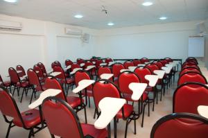 an empty room with red chairs and a whiteboard at Hotel Linhatur in Linhares