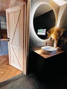 a bathroom with a sink and a mirror and a door at Ostoya Zawory -domki premium ,strefa relaksu, basen in Zawory