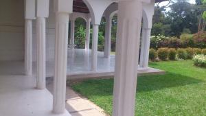 a white gazebo with columns in a yard at Egg Botanical View in Entebbe