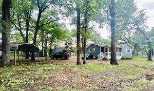 a house and a car parked in a yard with trees at The Hickory House with Firepit- Boat Ramp Access to Cedar Creek Lake in Tool