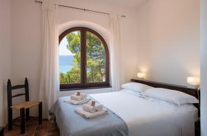 Un dormitorio con una cama y una ventana con toallas. en Villa Eliana sul Mare, en Porto Pino 25 fotos más