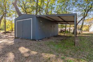a shed with a blue door in a field at The Hickory House with Firepit- Boat Ramp Access to Cedar Creek Lake in Tool