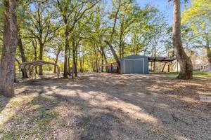 a shed in the middle of a forest with trees at The Hickory House with Firepit- Boat Ramp Access to Cedar Creek Lake in Tool