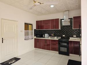 a kitchen with brown cabinets and a black stove at MacCarthy Residence in Accra