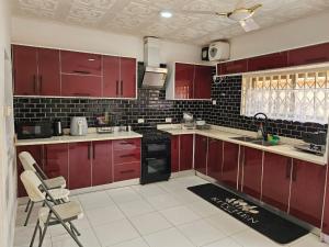 a kitchen with red cabinets and black appliances at MacCarthy Residence in Accra