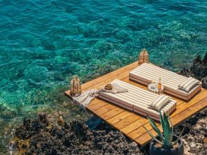 a wooden dock with two lounge chairs on the water at Sewelo Suites - Beachfront Boutique Suites in Skinária