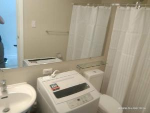 a bathroom with a toilet and a sink and a mirror at Modern & Minimalist Space Azure North Residences in San Fernando