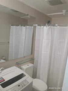 a bathroom with a white shower curtain and a toilet at Modern & Minimalist Space Azure North Residences in San Fernando
