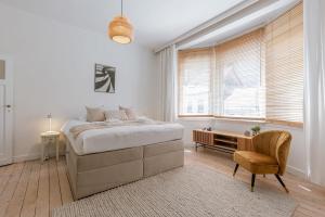 a white bedroom with a bed and a chair at Huswell - Relaxing Holiday Home with Private Sauna in Ostend