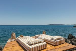 a dock with four lounge chairs on the water at Sewelo Suites - Beachfront Boutique Suites in Skinária +14 photos