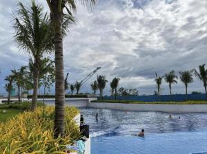 a pool with palm trees and people in the water at Modern & Minimalist Space Azure North Residences in San Fernando +8 photos