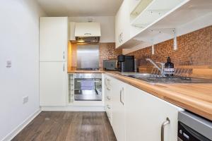 a kitchen with white cabinets and a wooden counter top at Bright, modern 2 bedroom house with free parking! in Edinburgh