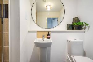 a white bathroom with a sink and a mirror at Bright, modern 2 bedroom house with free parking! in Edinburgh +23 photos