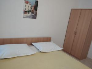 a bed with two pillows sitting next to a cabinet at Guest house Milic in Makarska