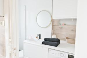 a white bathroom with a sink and a mirror at Appartement Cosy and Quiet Paris Villette in Le Pré-Saint-Gervais