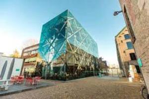a glass building with tables and chairs in front of it at Luxe Studiomuseumgebiedeftelinguvt in Tilburg