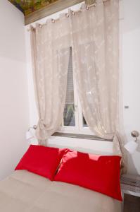 a bed with a red pillow in front of a window at A Casa di Lu Na in Bologna