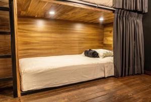 a bed in a room with a wooden wall at Homestal California Hostal en Tlaquepaque in Guadalajara +55 photos