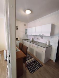 a kitchen with white cabinets and a sink and a table at Ema Apartmani in Vinkovci