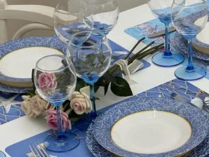 a table with four wine glasses and plates and flowers at Melficta House in Molfetta