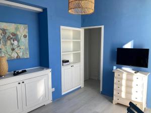 a blue room with a tv and a white dresser at Al Mari Suites in Ponza