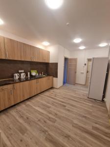 an empty kitchen with wooden cabinets and a refrigerator at Pie Parka in Alūksne