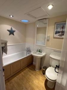 a bathroom with a toilet and a tub and a sink at Courtyard Farm Cottages in Boscastle +96 photos