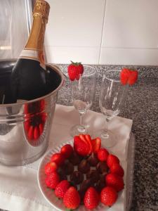 a plate of strawberries and a bottle of wine and wine glasses at Hotel Jorge V in Mirandela