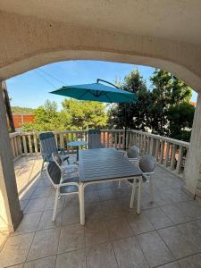 a table and chairs with an umbrella on a deck at Kuća Roza in Rukavac