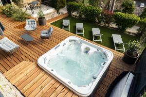 a hot tub sitting on a wooden deck with chairs at Gîte petite lauze in Espalion