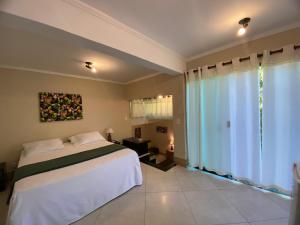 a bedroom with a bed and a large window at Pousada Sol e Cia Tur in Caraguatatuba