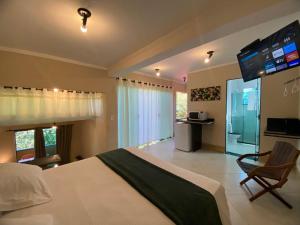 a bedroom with a large bed with a tv on the wall at Pousada Sol e Cia Tur in Caraguatatuba