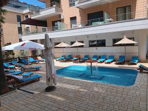 a pool with chairs and umbrellas next to a hotel at Diamond Hill Apartment in Vlorë