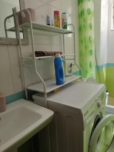 a laundry room with a washing machine and a shelf at Glen's Apartament at Qerret Beach in Golem