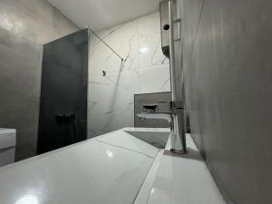 a white bathroom with a sink and a mirror at Gigi Apartment by eluxory in Skopje