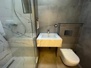 a bathroom with a sink and a shower and a toilet at Gigi Apartment by eluxory in Skopje