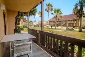 サウス・パドレ・アイランドにあるPelicans Perch Charming 1BR Near Beach with Patio 160のヤシの木が植えられたバルコニー(テーブル、椅子付)