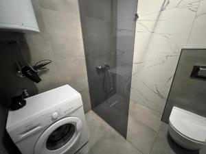 a bathroom with a shower and a washing machine at Gigi Apartment by eluxory in Skopje