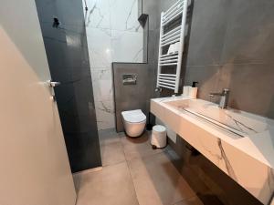 a bathroom with a sink and a toilet at Gigi Apartment by eluxory in Skopje