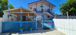 a house with a blue gate and a white fence at Casa Epat in 2 Mai