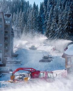 ein Bulldozer im Schnee mit Bäumen im Hintergrund in der Unterkunft STENATA Sport Apartments in Pamporowo