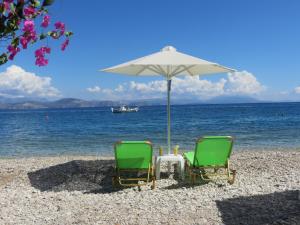 two chairs and an umbrella on a beach at Blue Sky Studios in Xiropigado