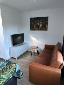 a living room with a couch and a tv at Casa Delfts Blauw in Mierlo +12 photos