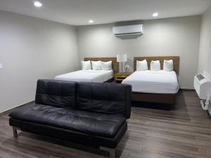 a hotel room with two beds and a leather couch at Days Inn by Wyndham El Centro in El Centro