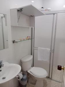 a white bathroom with a toilet and a sink at Hotel Cafetero Valparaíso in La Vega