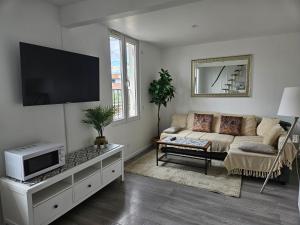 a living room with a couch and a flat screen tv at spacieux duplex Stade de France 24 pour 4 personnes in Saint-Denis